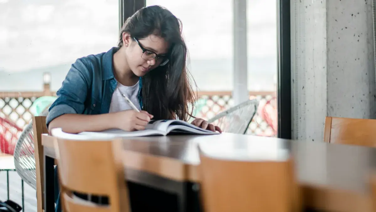 Student studying and taking notes at a table