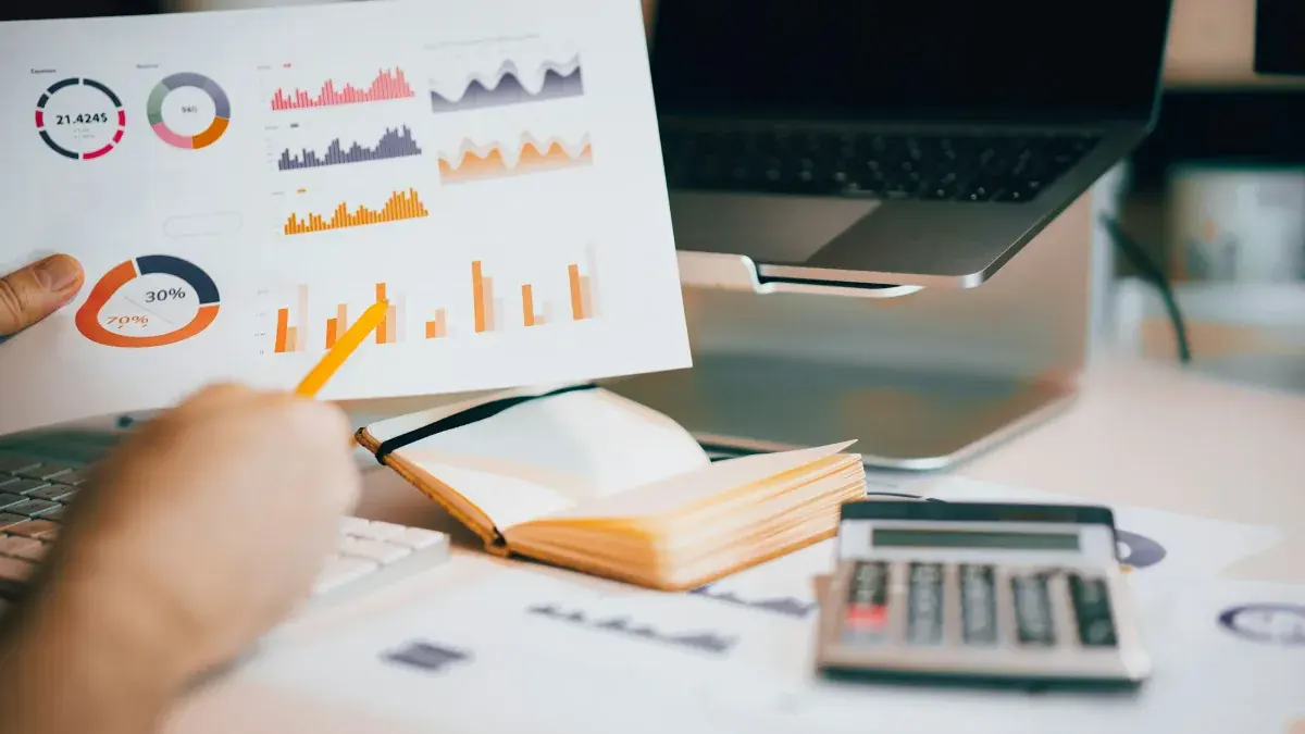 Financial charts, a notebook and a calculator on a desk