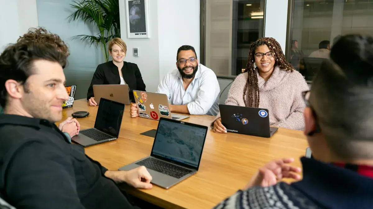 Small team meeting around a table with laptops